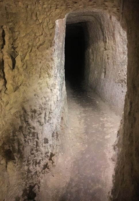 A narrow corridor leading to blackness in the catacombs of the Wignacourt Museum.